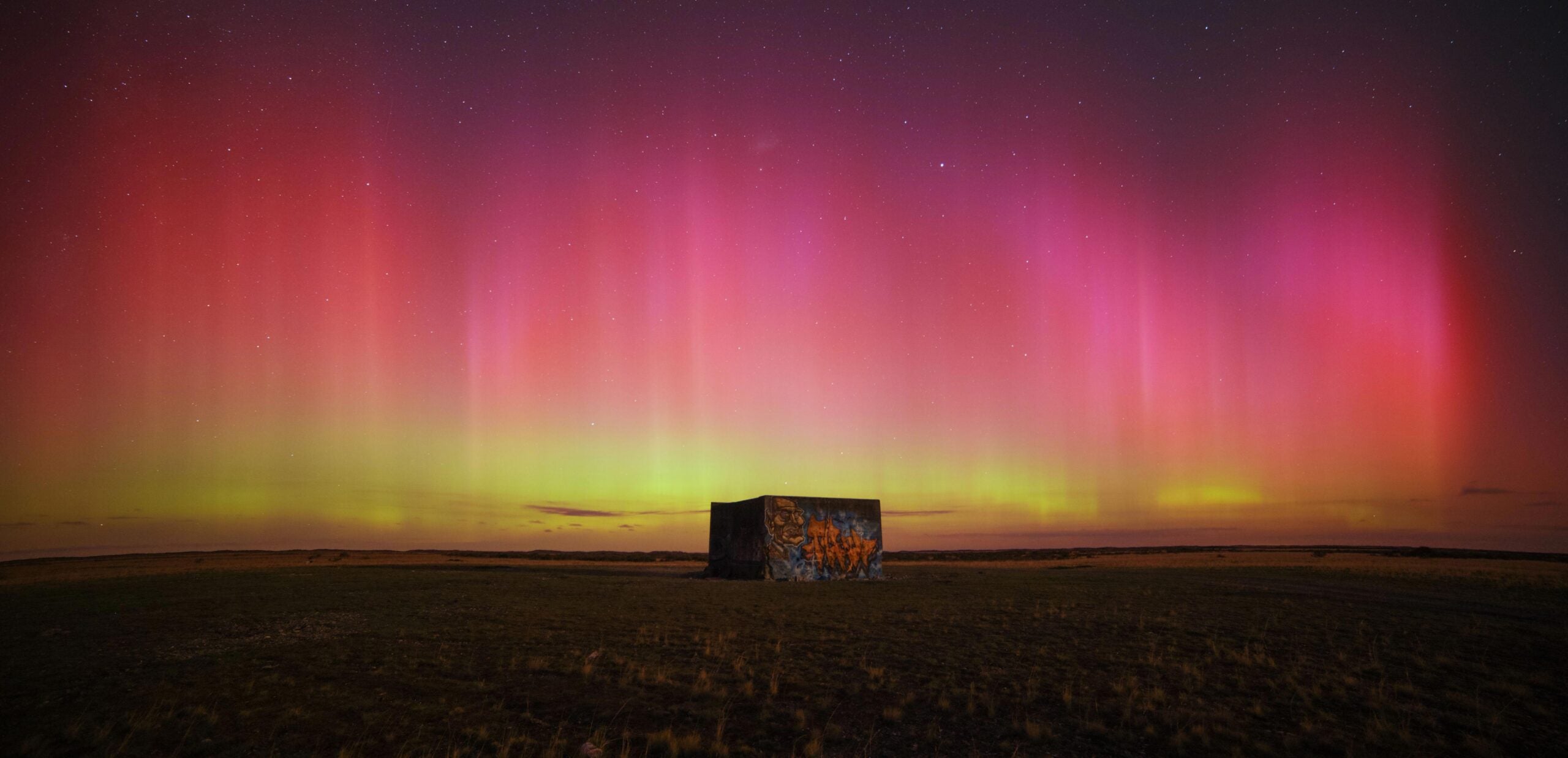 Yellow pink and red aurora over a small building