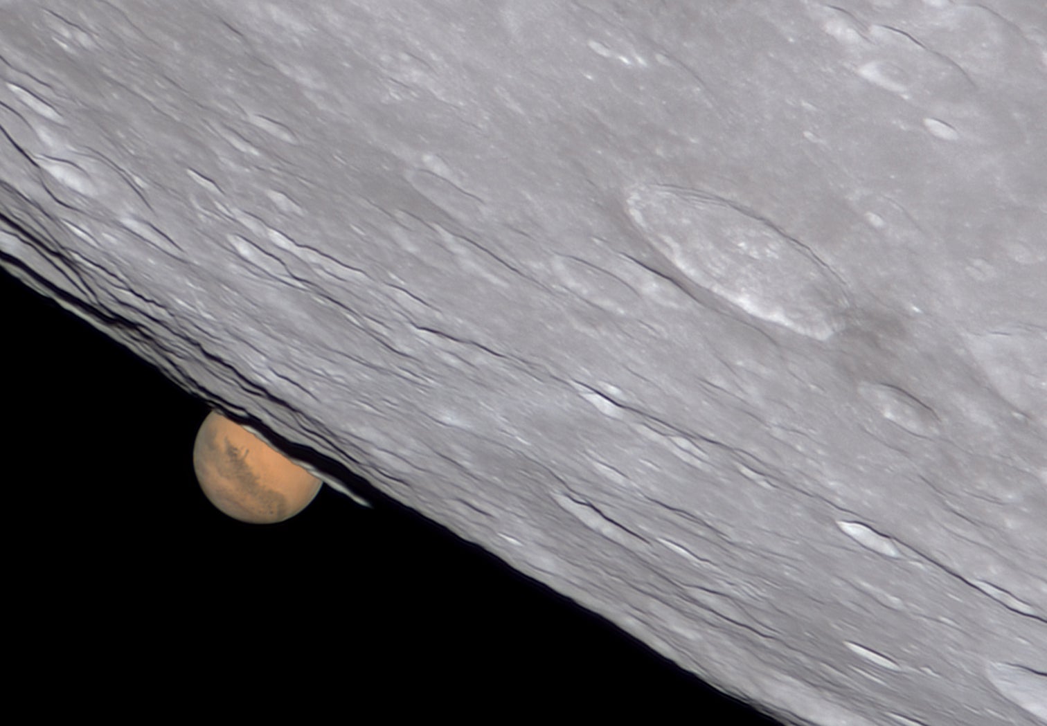 Closeup of the moon with mars peeking out behind smaller