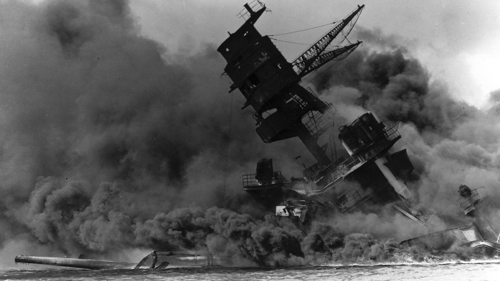 A black and white archival photo of the USS Arizona sinking during the attack on Pearl Harbor on December 7, 1941.