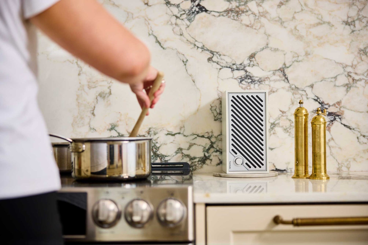 Tivoli Audio new white Model Two Digital streaming speaker in a kitchen with a woman cooking