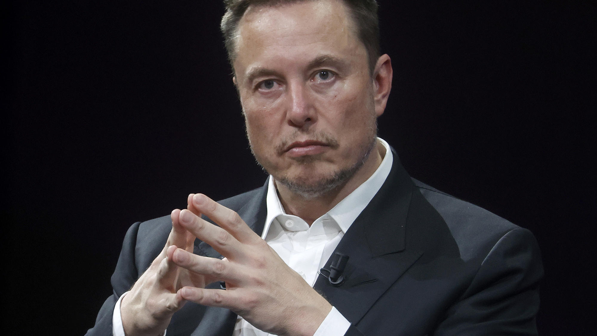 Elon Musk sitting with finger tips touching in steeple shape