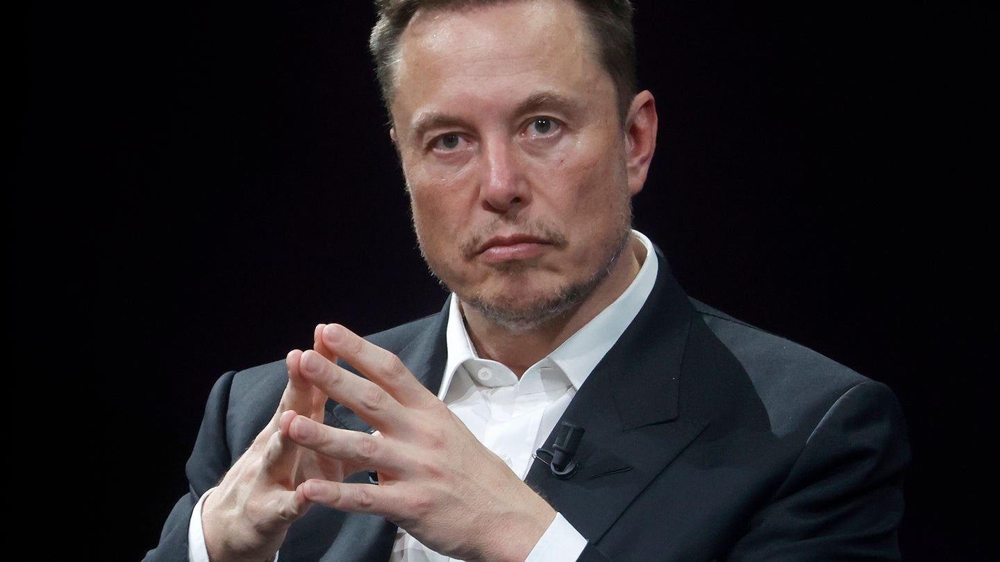 Elon Musk sitting with finger tips touching in steeple shape