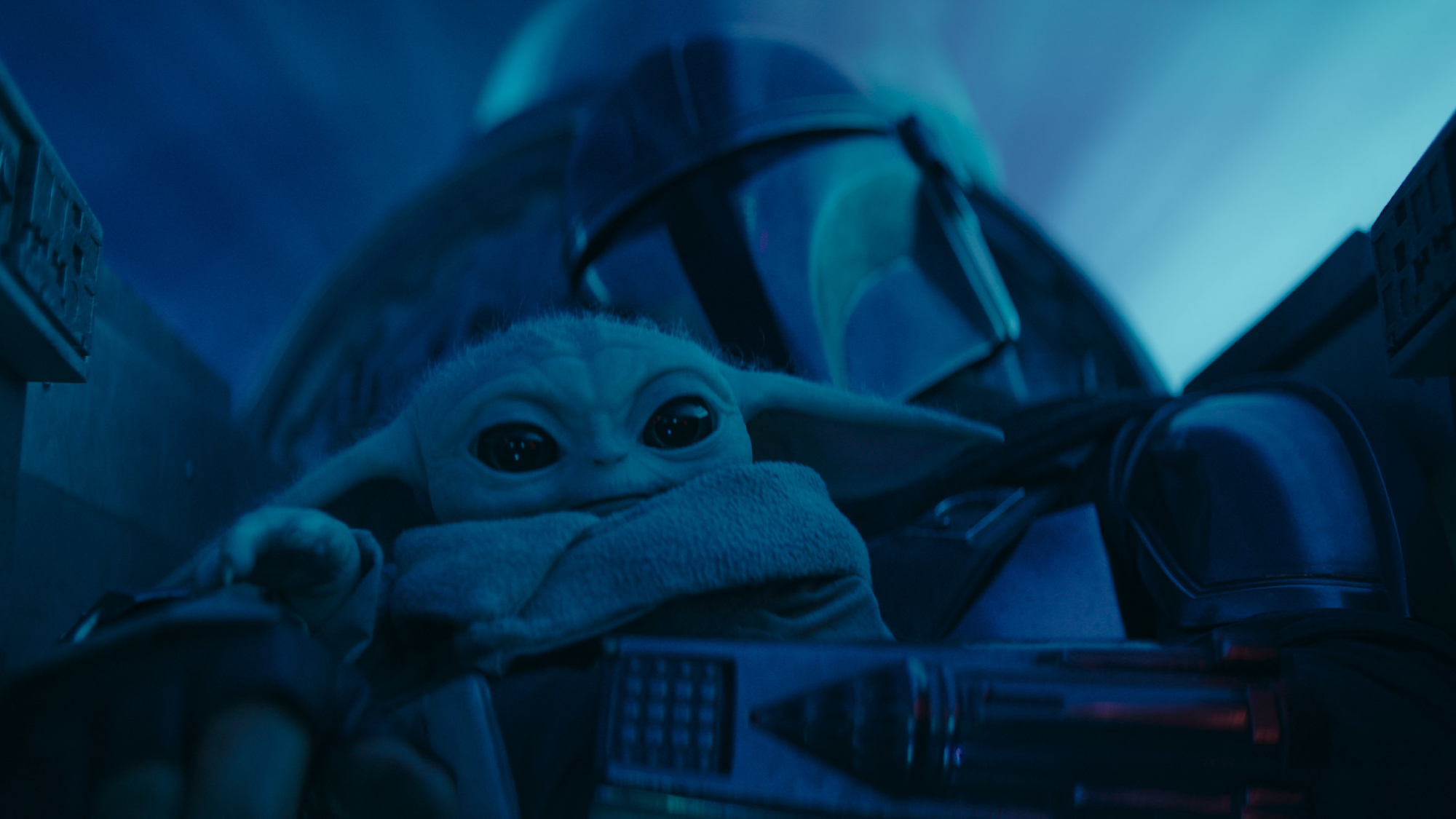 Din Djarin (the Mandalorian) in his spaceship with Grogu (baby Yoda) on his lap, traveling through hyperspace.