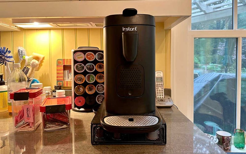 A black Instant Pot pod coffee machine on a counter with Nespresso and Keurig pods
