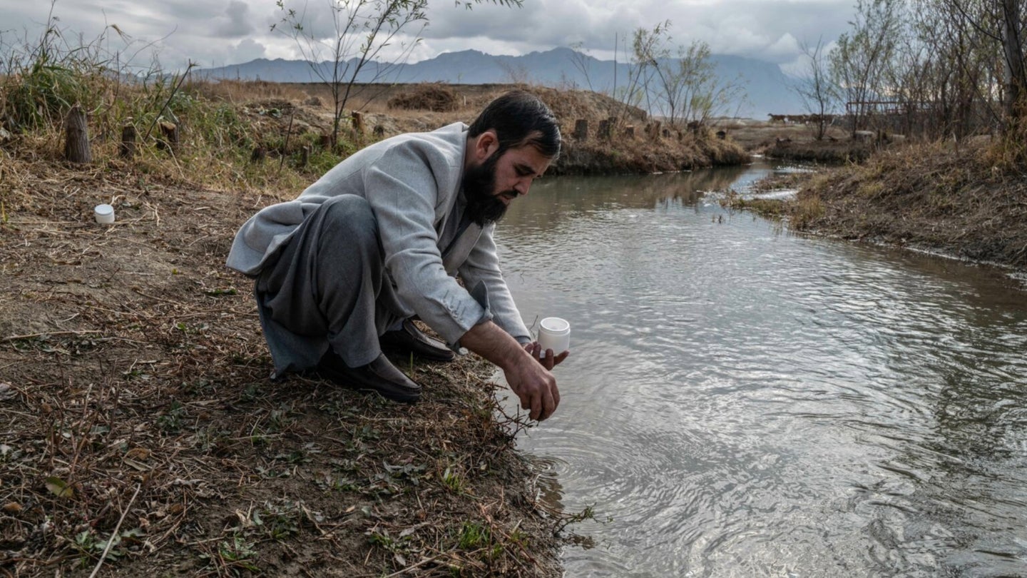 An Afghan scientist gathers water and soil samples at a water outflow from Bagram Airfield, formerly America's largest military base in Afghanistan. 
