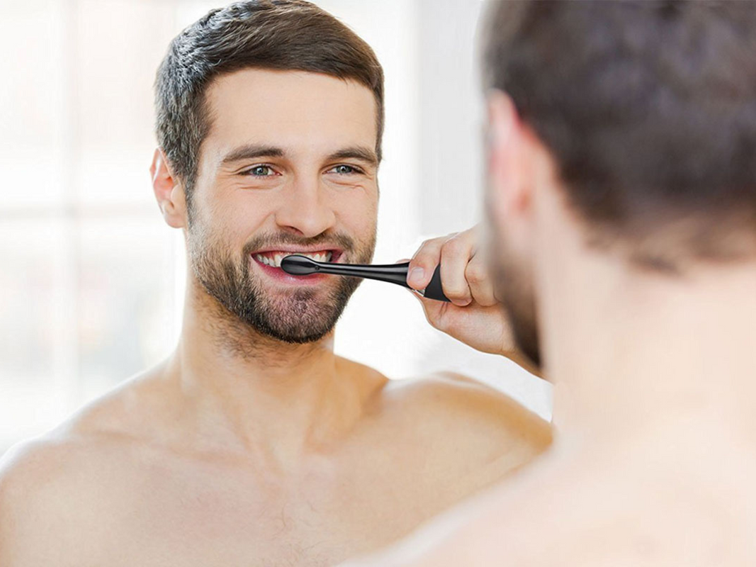 A person brushing their teeth in the mirror
