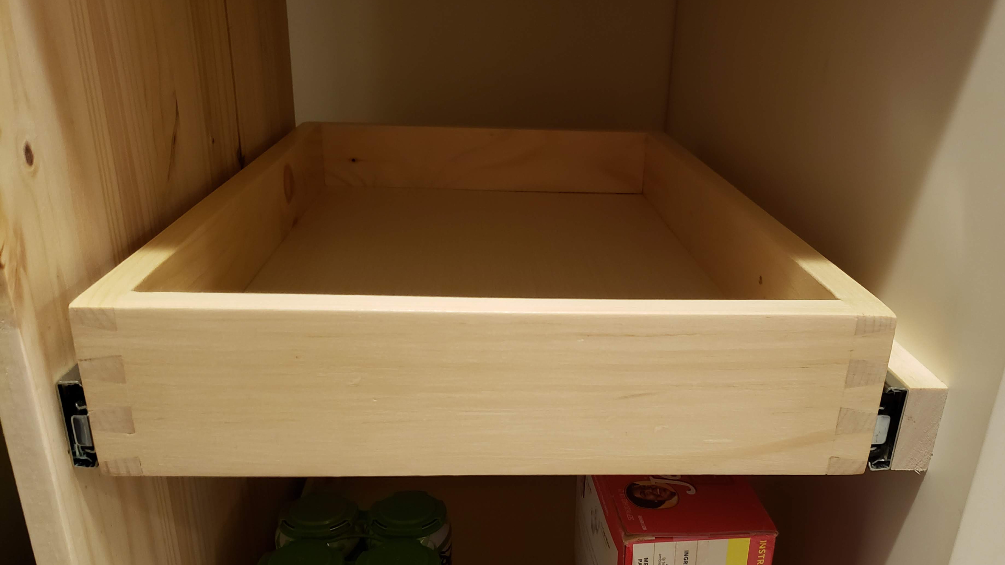 A drawer inside a cabinet, after someone has installed the drawer slides to hold it in place.