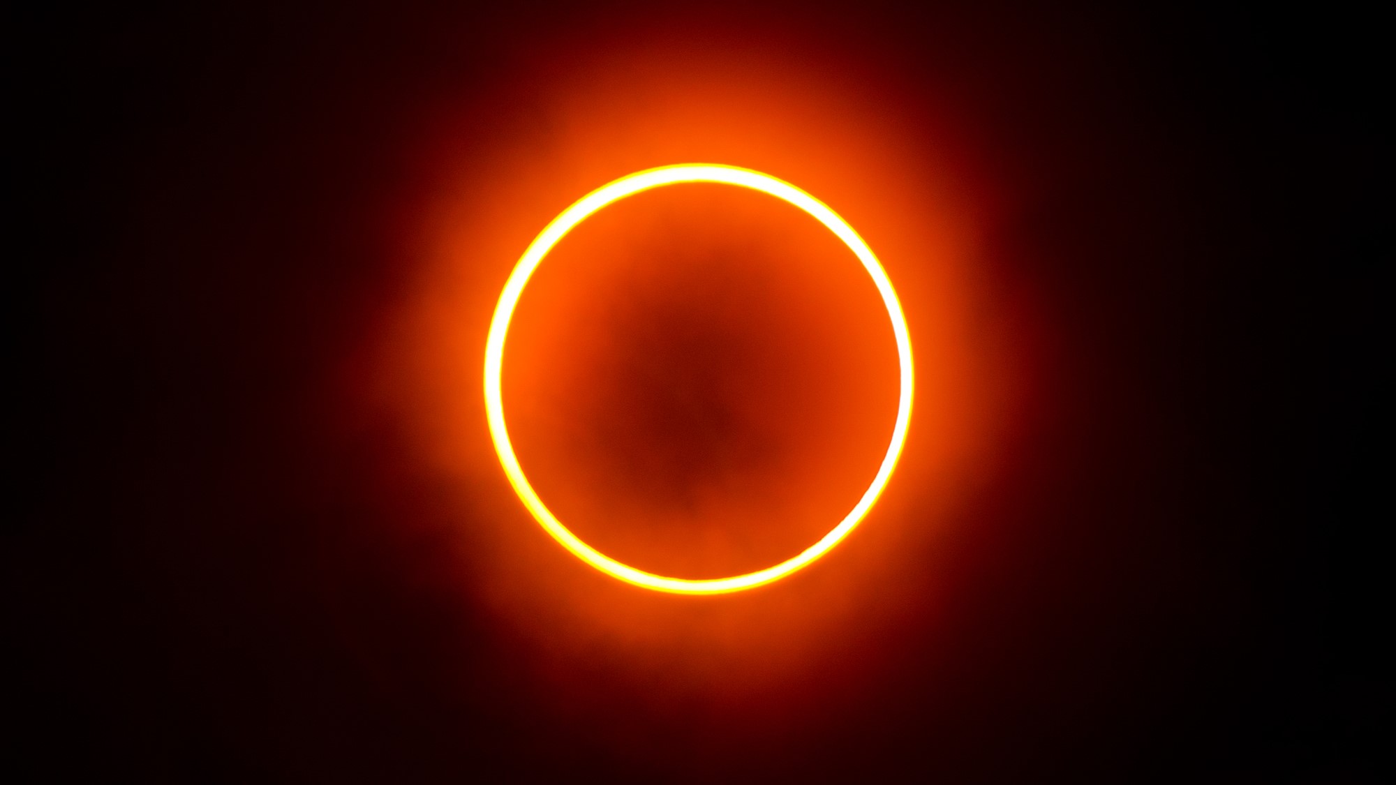 An orange ring around the dark moon eclipsing the sun.