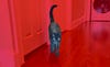 Black cat walks down hallway with tail up. Red filter on photo.