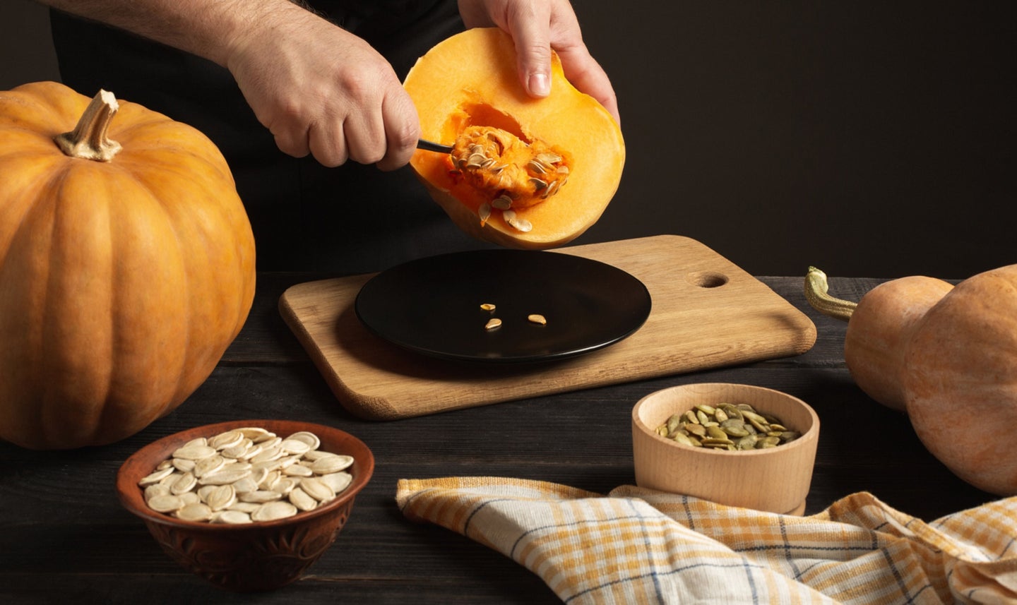 Person cooking whole pumpkin and roasting pumpkin seeds to get pumpkin health benefits