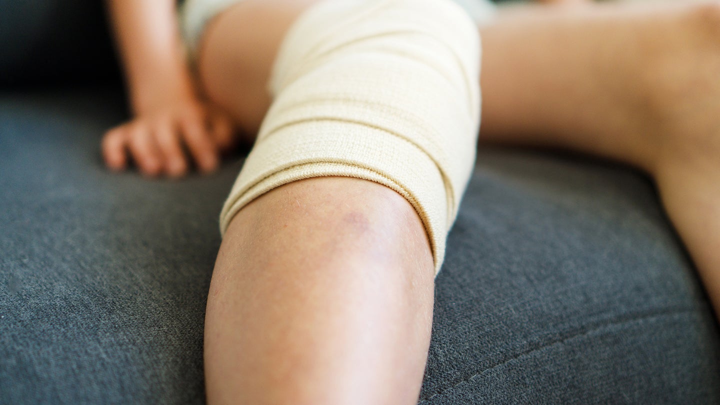 Child knee with gauze bandage. Close-up view.