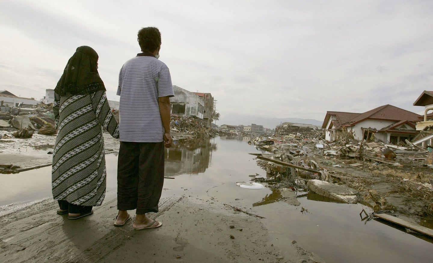 A woman and man in Indonesia view the destruction from a tsunami.