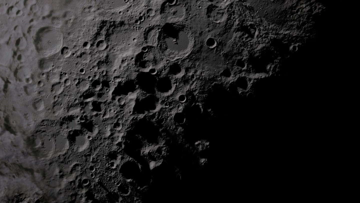Pale craters on the moon's lunar surface, with dark shadows below.