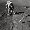 Apollo 17 astronaut Harrison Schmitt stands on the moon's surface in 1972. Schmitt is probing various moon rocks and collecting samples to return back to Earth.