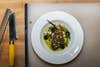 A filet of a fish called scup in a bowl with kelp vinegar and sea beans sits on a countertop.