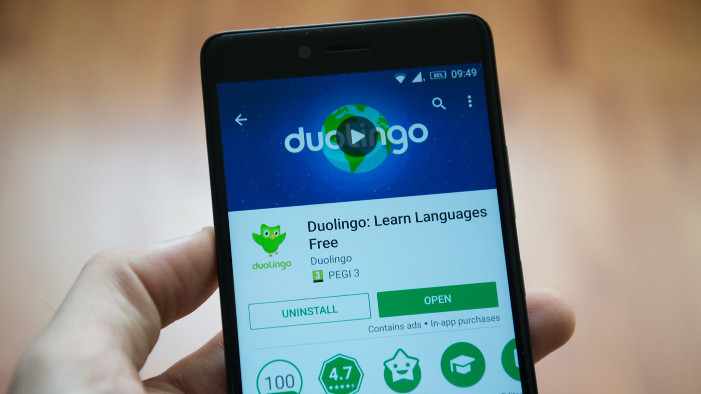 A person holding a smartphone featuring Duolingo, one of the best free language learning apps.