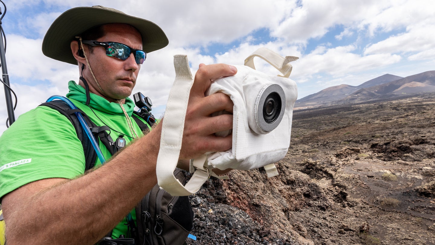 Man holding HULC lunar camera in rocky outdoor environment