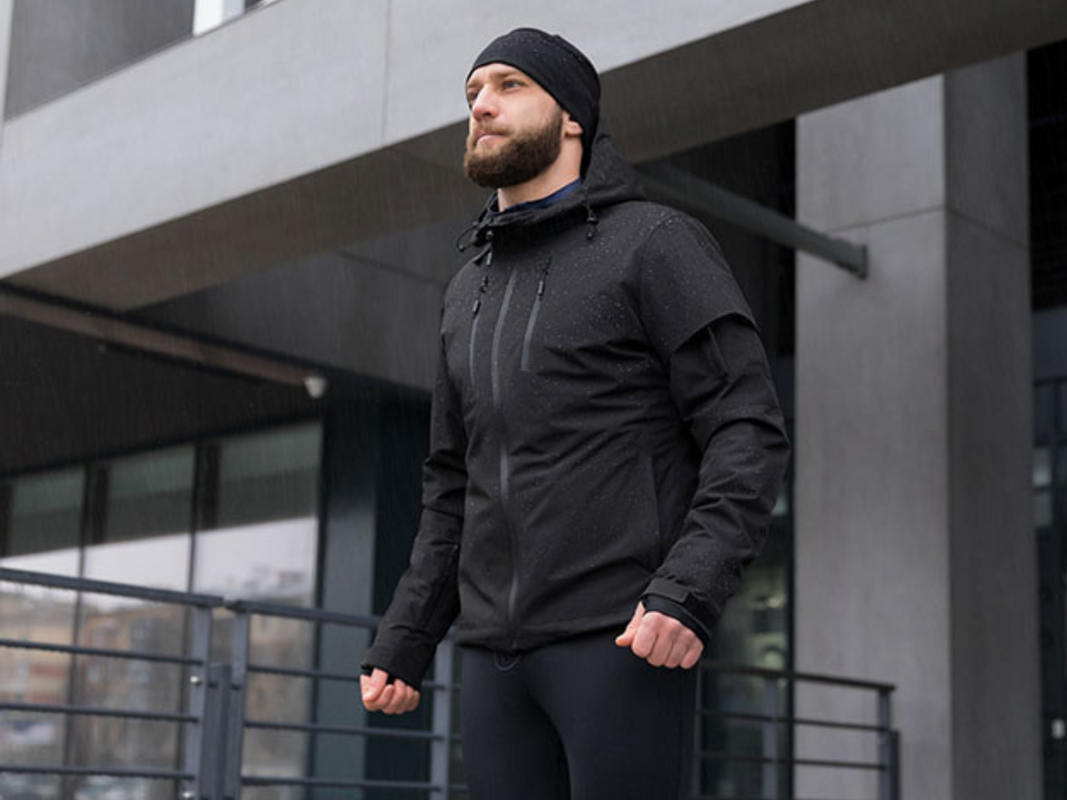 A person wearing a black graphene heated jacket outside of a building