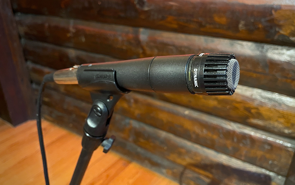 Shure SM57 microphone on a stand in front of a wood wall