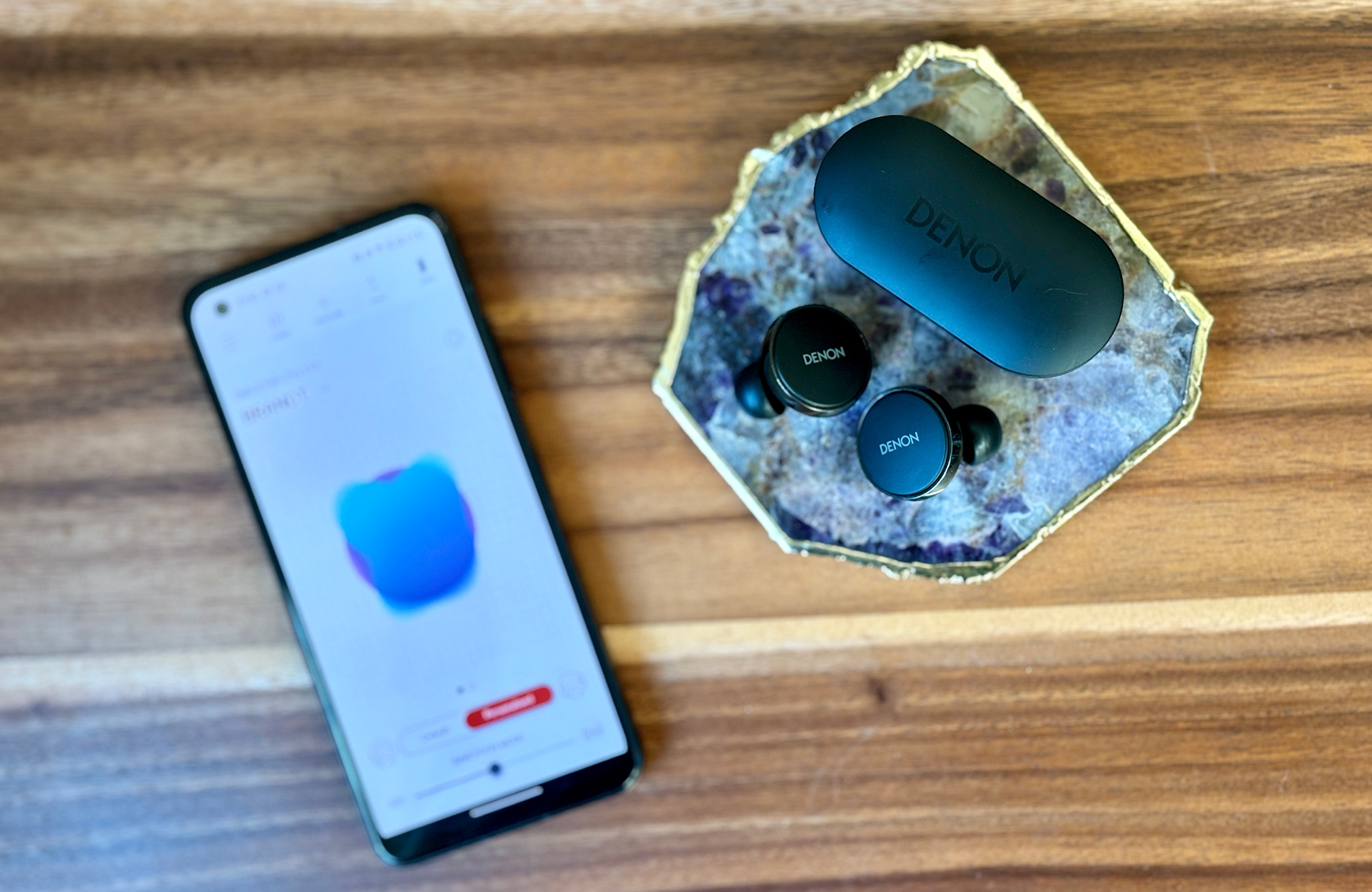 Denon PerL Pro True Wireless Earbuds next to an ASUS ZenFone 10 showing a personalized listening profile in the Denon app
