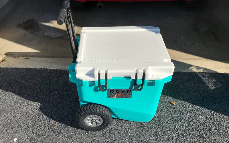 A blue RovR RollR 45 Wheeled Cooler sits on a driveway.