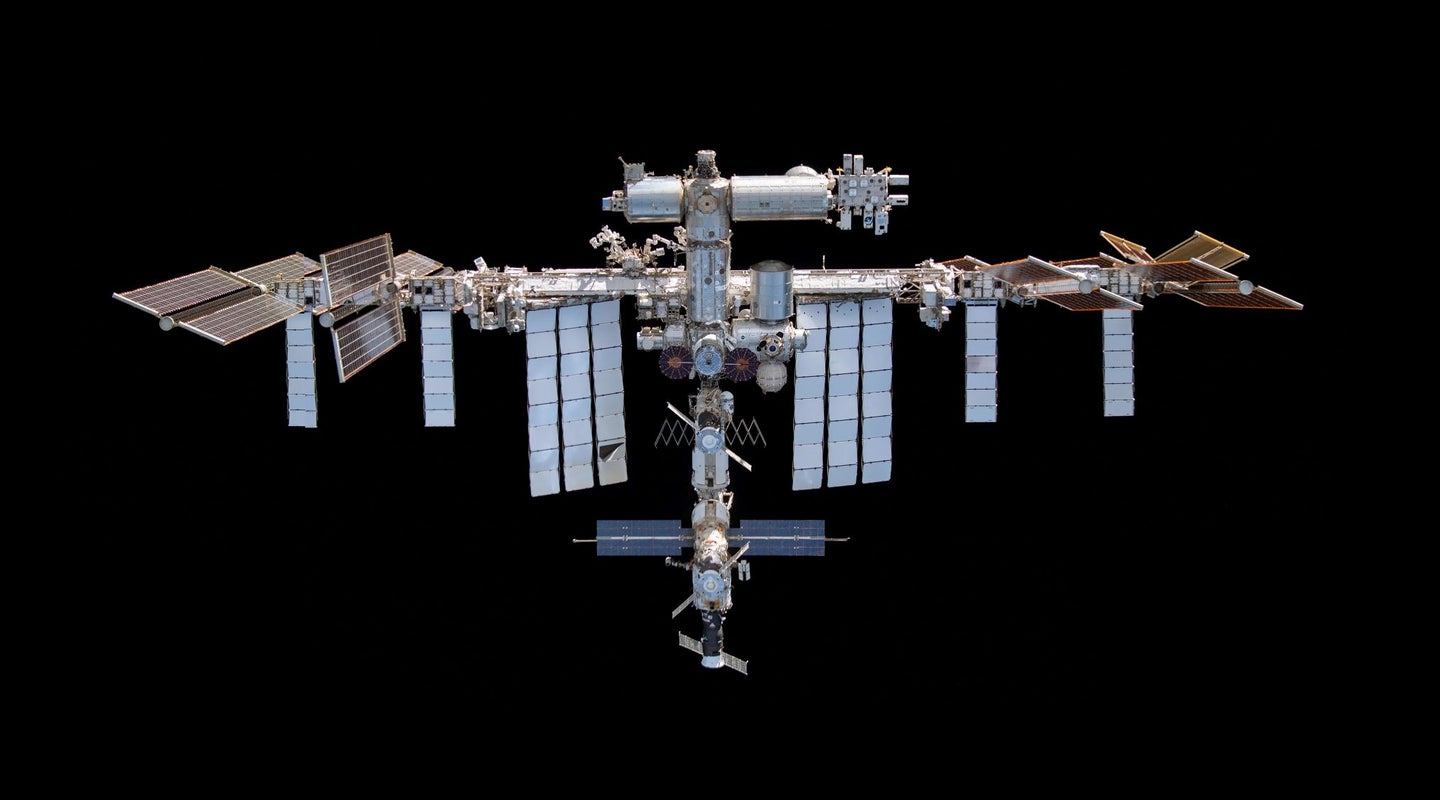 The silver structure of the International Space Station against the black backdrop of space.