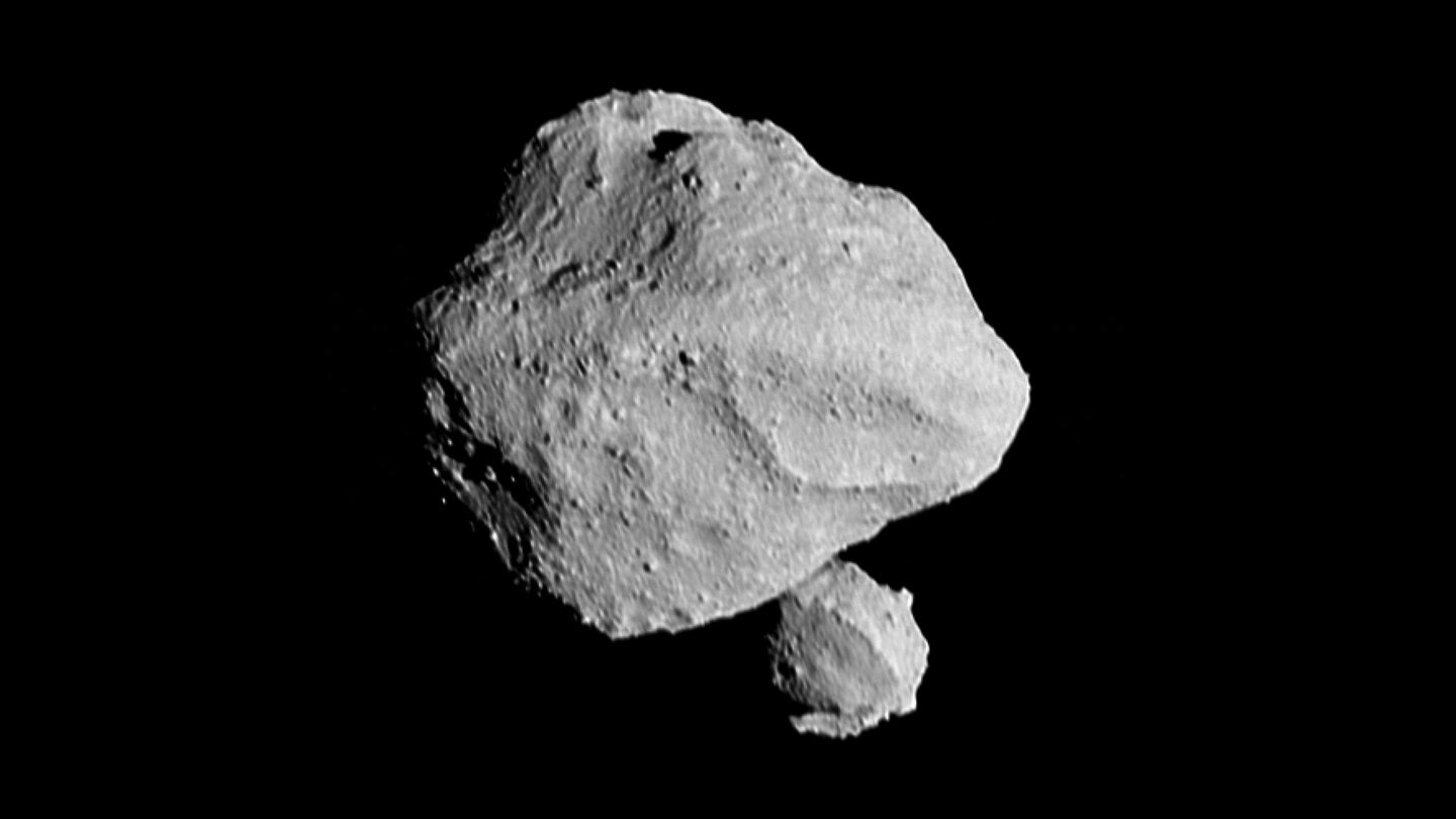 A large asteroid with a smaller asteroid orbiting it. This image shows the “moonrise” of the satellite as it emerges from behind asteroid Dinkinesh as seen by the Lucy Long-Range Reconnaissance Imager. This image was taken by NASA’s Lucy spacecraft at 12:55 p.m. EDT on November 1, 2023, within a minute of closest approach, from a range of approximately 270 miles. From this perspective, the satellite is behind the primary asteroid. The image has been sharpened and processed to enhance contrast.