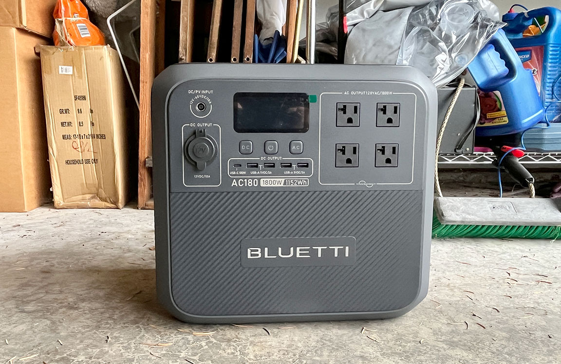 Grey square Bluetti AC180 portable power generator sitting in a garage