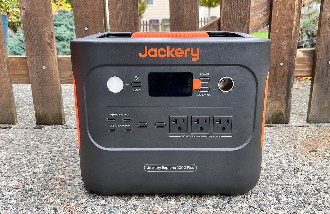 Orange and grey rectangular Jackery 1000 Plus portable generator on a patio