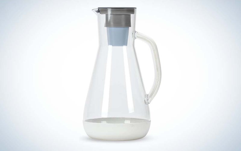A clear plastic pitcher with a gray water filter on top against a plain background.