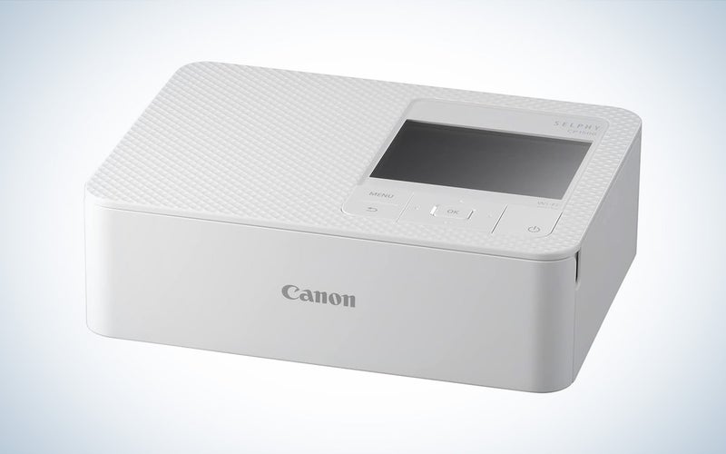 The white Canon Selphy CP1500 sublimation printer is placed against a white background with a gray gradient.