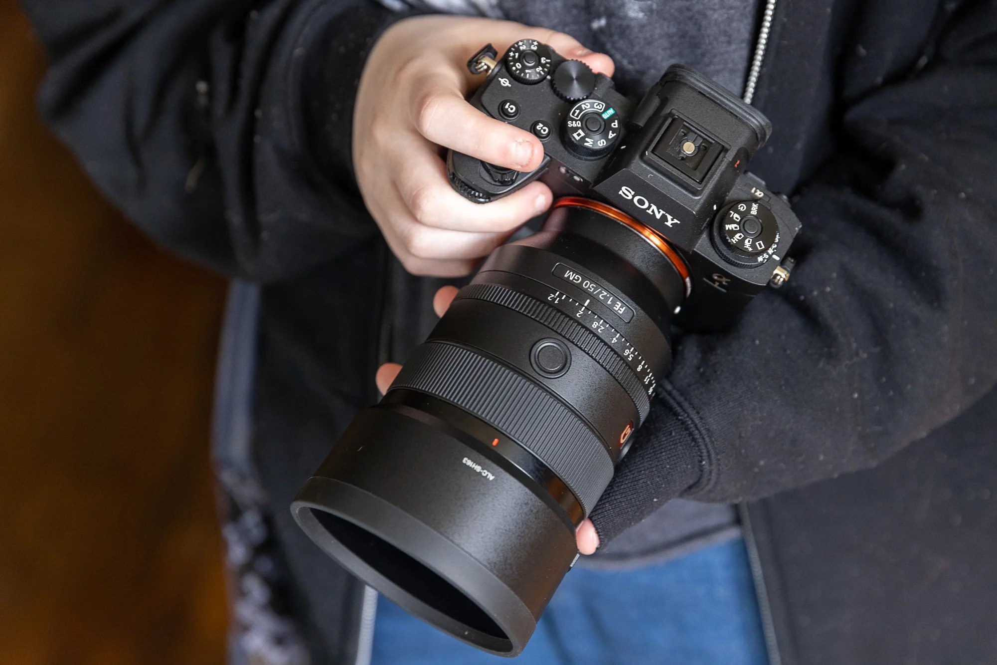 A hand holds the Sony a1 mirrorless camera in front of their body.