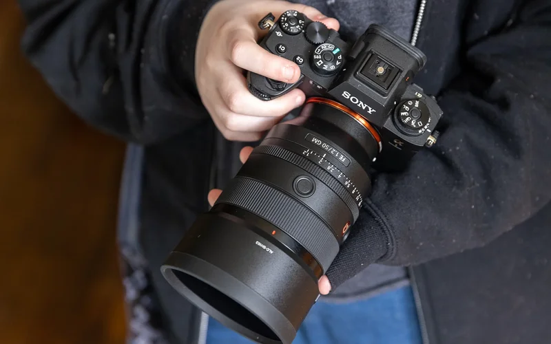 A hand holds the Sony a1 mirrorless camera in front of their body.