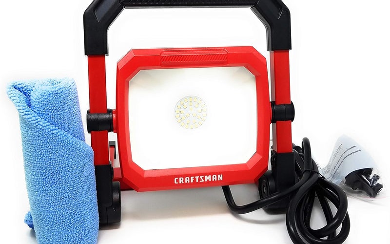 A red Craftsman LED light with a black handle and plug next to a blue microfiber towel.