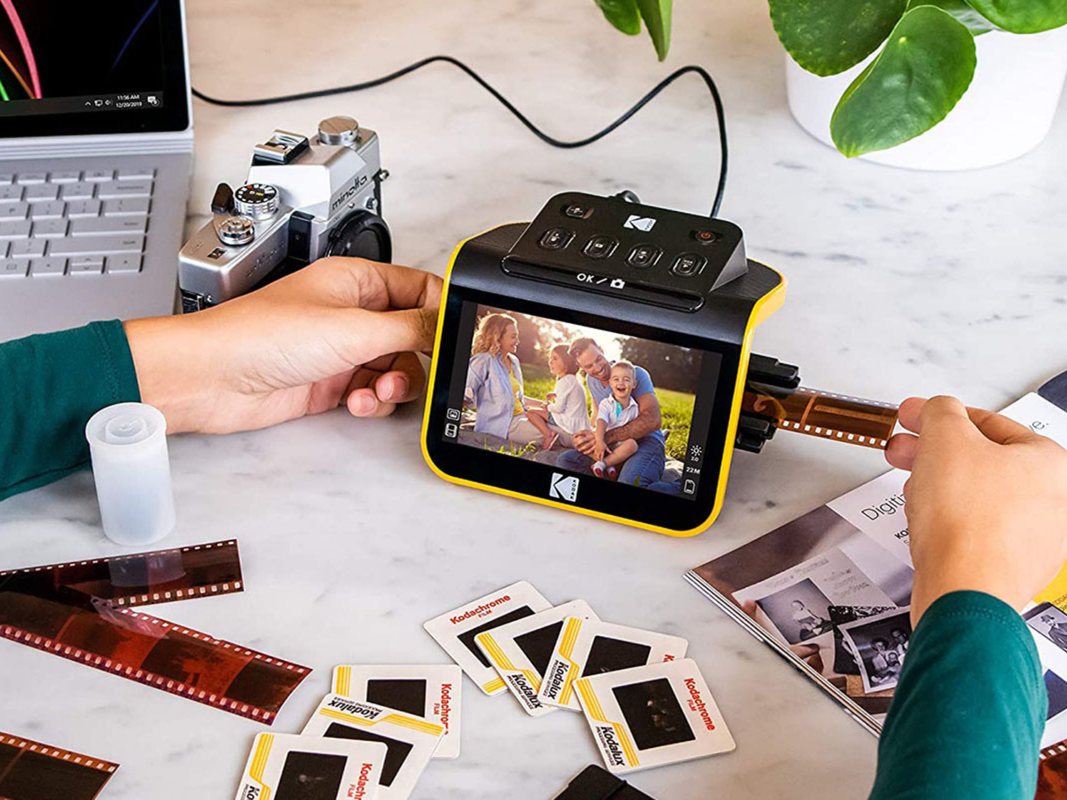 A person scanning photos using a yellow Kodak photo scanner