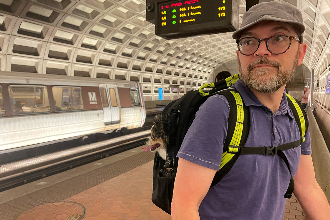 ROVERLUND pet backpack on my back holding a small dog watching trains in the DC metro