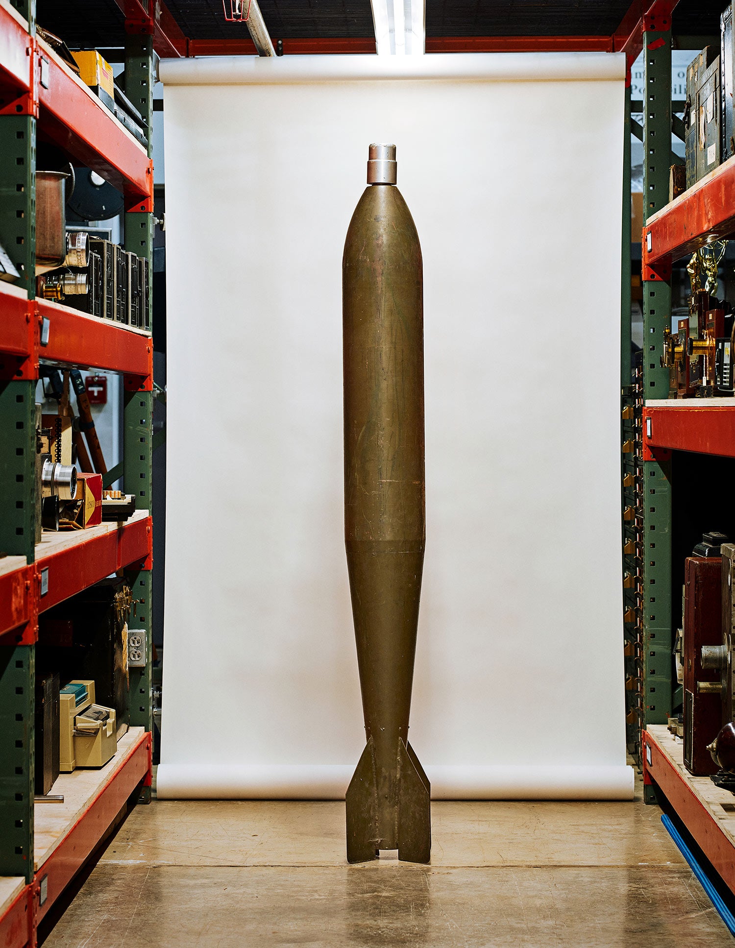a vintage flash bomb standing upright in the aisle of a camera museum in front of a photography backdrop