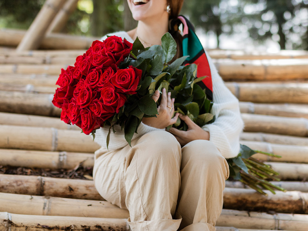 A person holding roses sitting on some logs