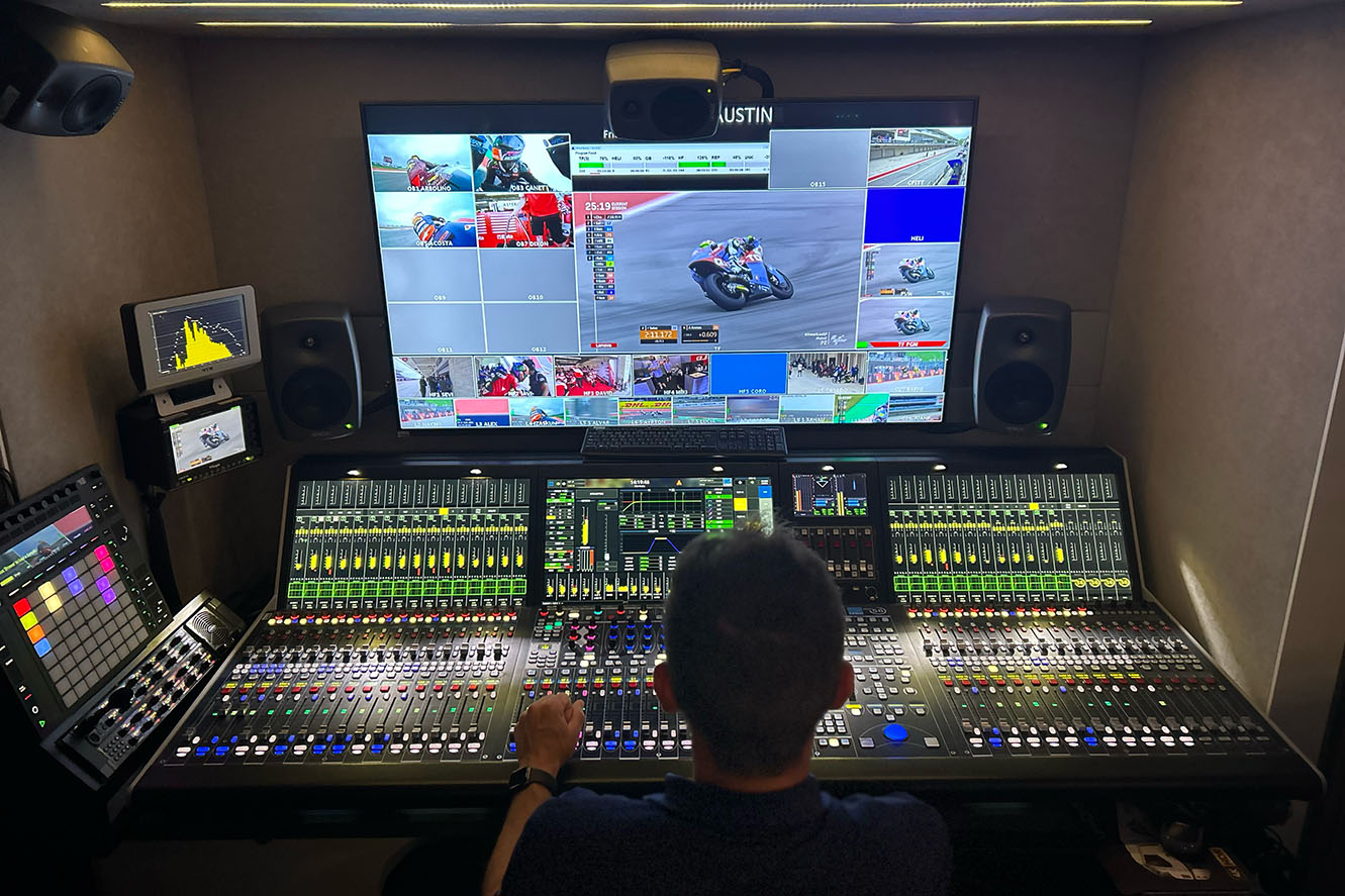 An audio engineer sits in-front of a large screen and a Lawo console mixing multiple channels of Audio- Technica mics for live broadcast