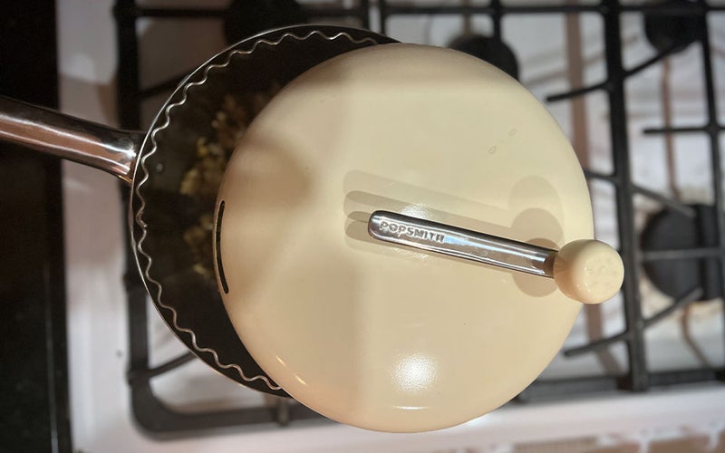 A cream Popsmith stovetop popper cooking on a white stove.
