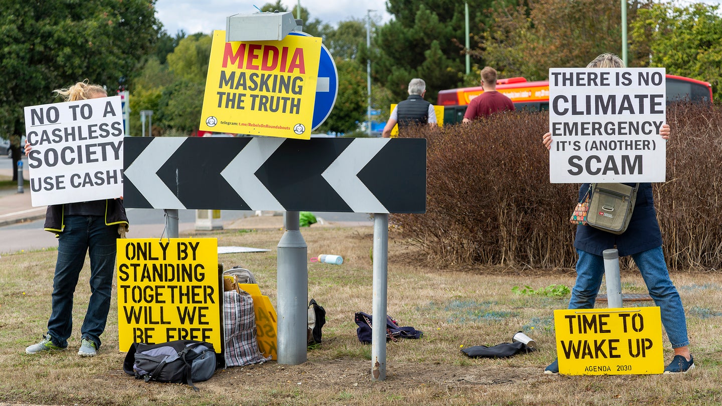 Conspiracy theorists protest at a busy roundabout in the village of Martlesham in Suffolk, England.