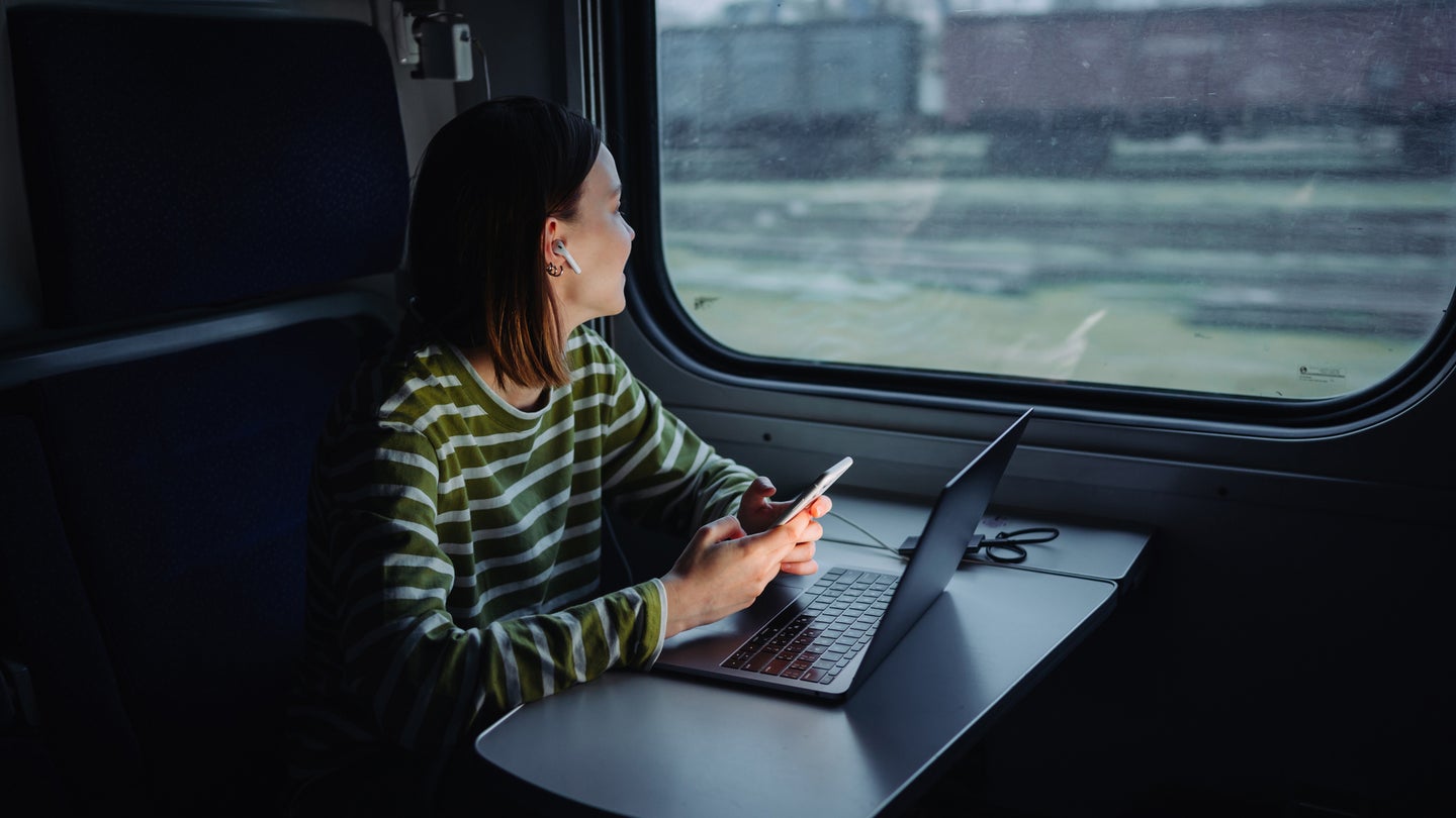 woman sitting on train using laptop and computer