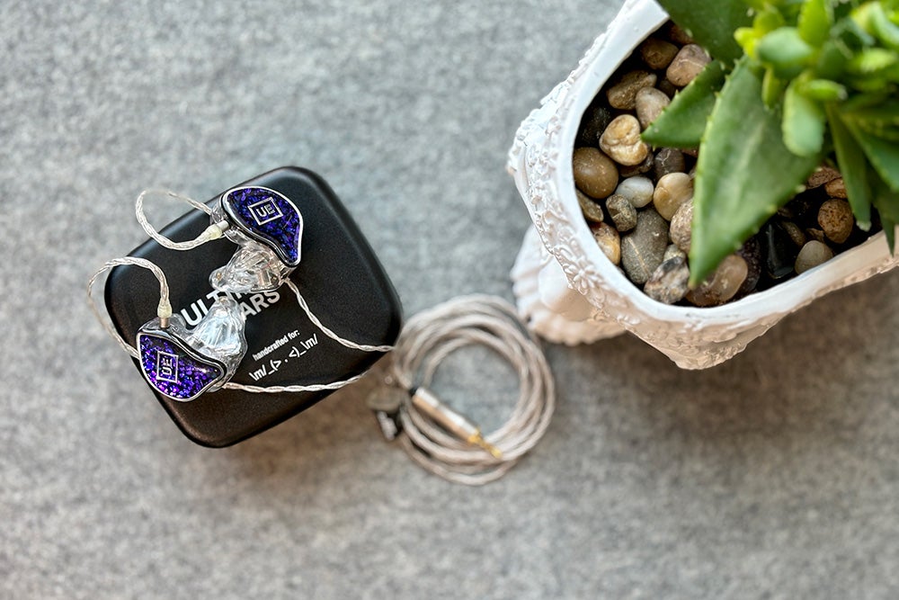 Amethyst and silver UE branded Premier custom molded in-ear monitors for performers on top of a black Ultimate Ears carrying case