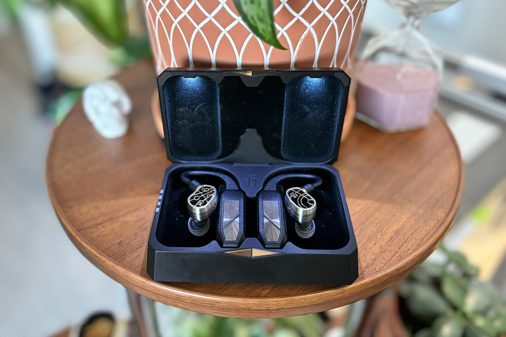 Silver. and gold-plated Campfire Audio Solaris Stellar Horizon hybrid IEMs attached to the iFi GO pods Bluetooth TWS adapters in a black illuminated case