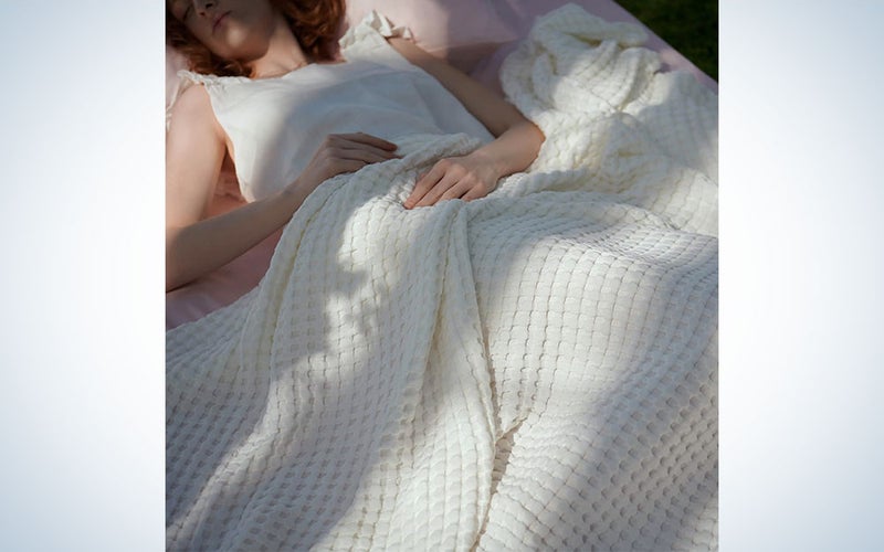 A person in bed laying under a white Bedsure Cooling Cotton Waffle Queen Size Blanket