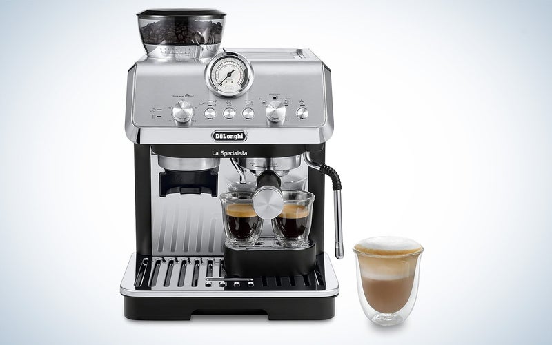De'Longhi La Specialista espresso machine on a plain background sitting next to a cappucino in a clear mug