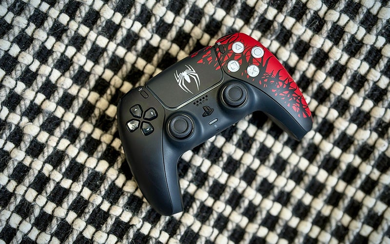 Black, red and white Spider-Man 2 skinned PS5 DualSense controller on a black and white pillow