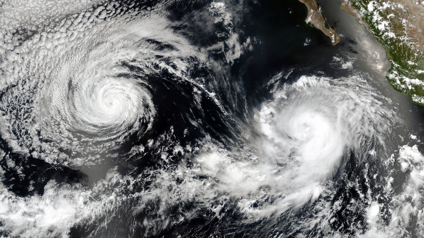 A satellite image of two cyclones over the ocean with land nearby.