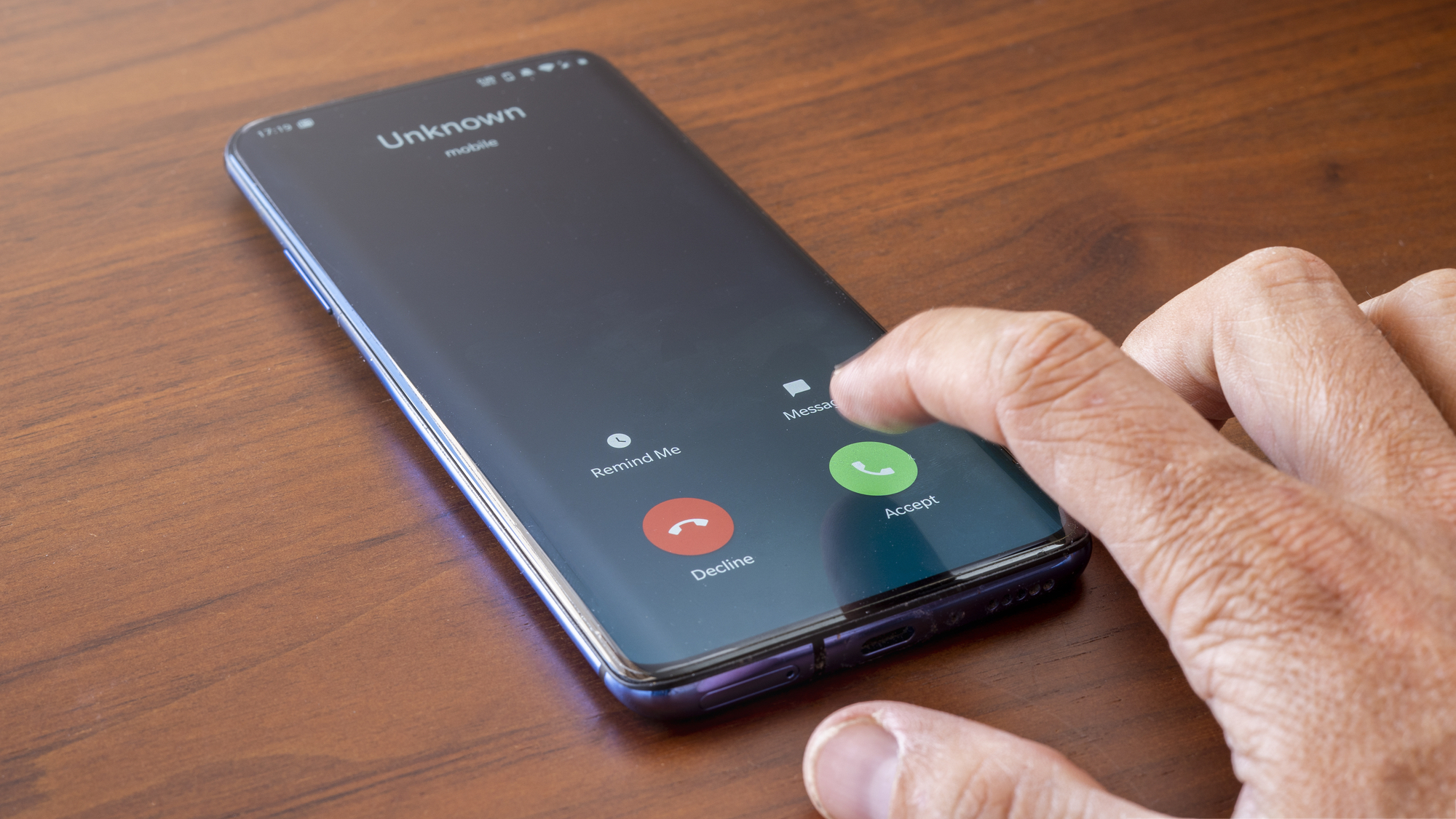 Hand reaching to press 'accept' on unknown smartphone call