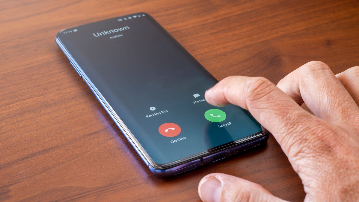 Hand reaching to press 'accept' on unknown smartphone call